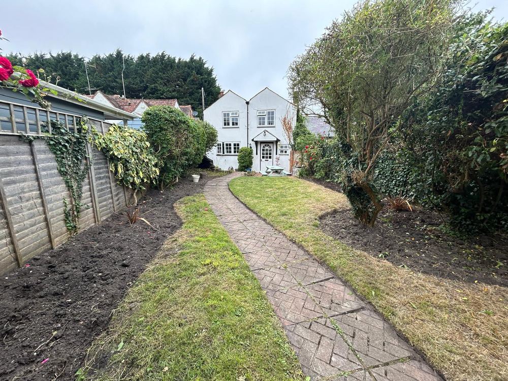 After: the same garden with the grass cut, the herringbone path clear and the borders along the fence dug over, a white house at the end