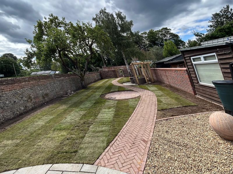 After &mdash; the same spot with new striped turf, a curving herringbone brick path, fresh gravel and an oak pergola
