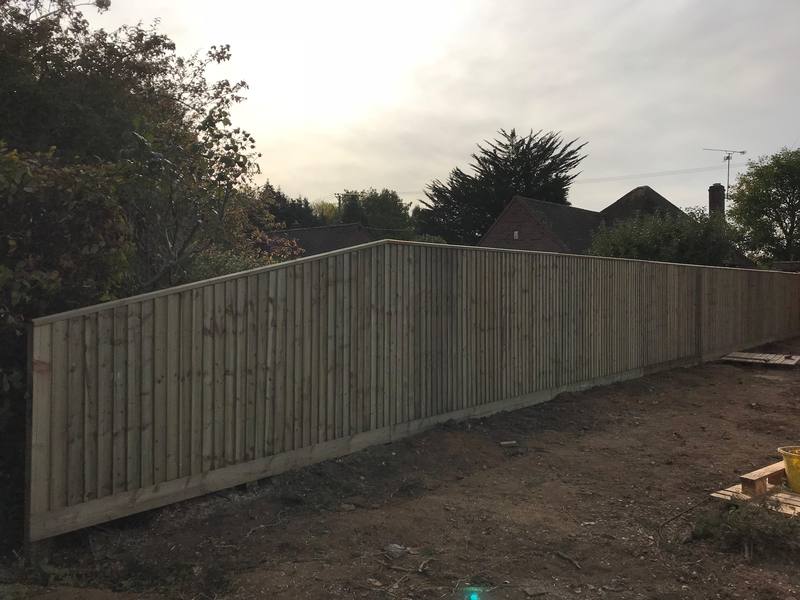 A long new closeboard fence with gravel boards along freshly cleared ground