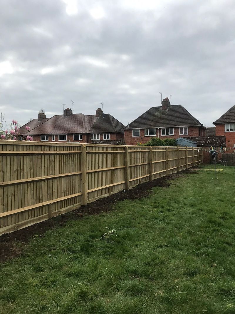 A new closeboard timber fence running the length of a garden boundary beside a lawn