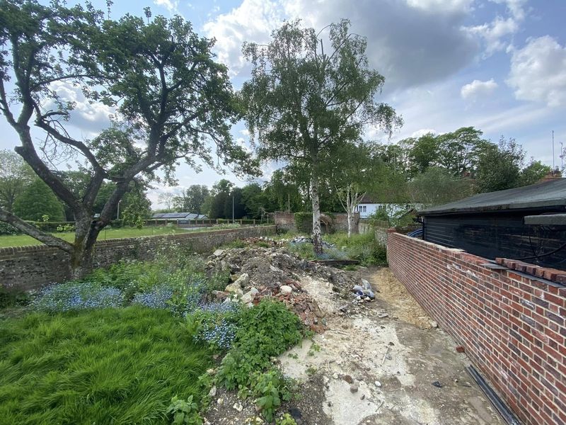 Before: the walled garden piled with rubble and overgrown with long grass and weeds